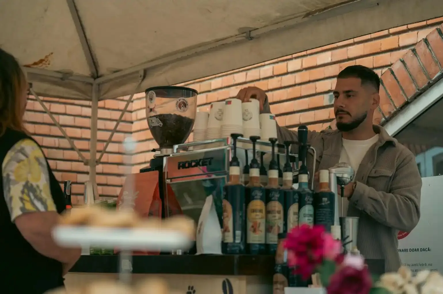 Cristian pregătind cafea la aparatul de espresso, sub cort