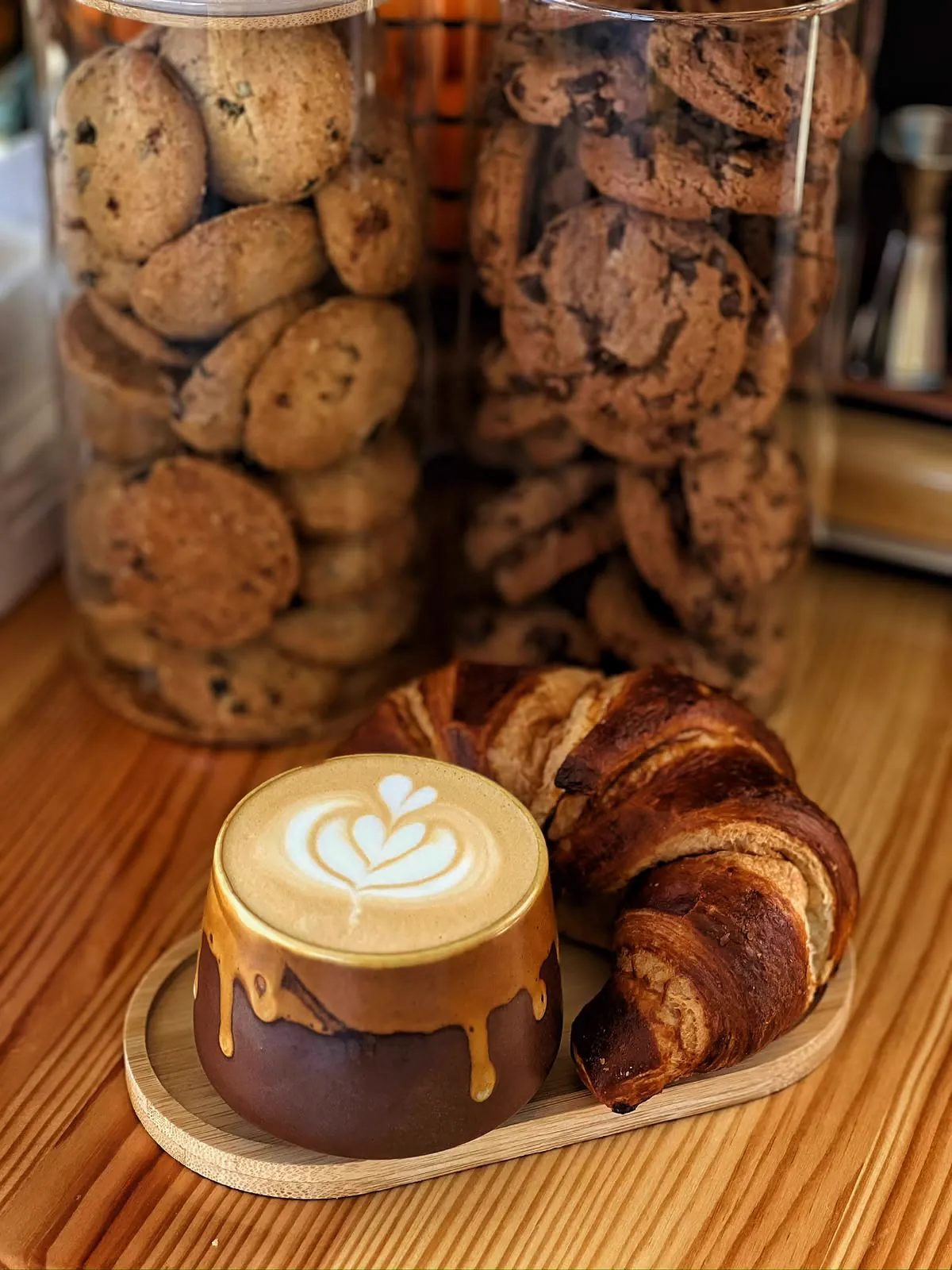 Latte cu latte art lângă un croissant